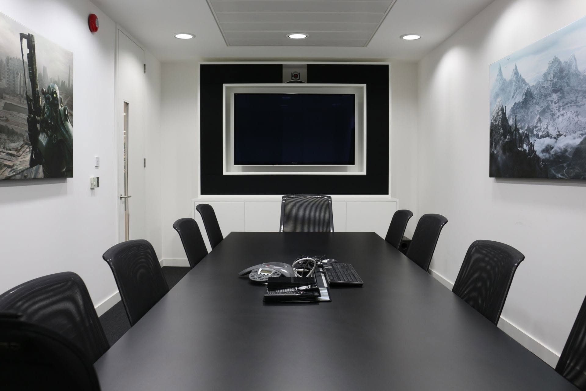 Boardroom with a wall-mounted display, conference camera and conference phone on the meeting table